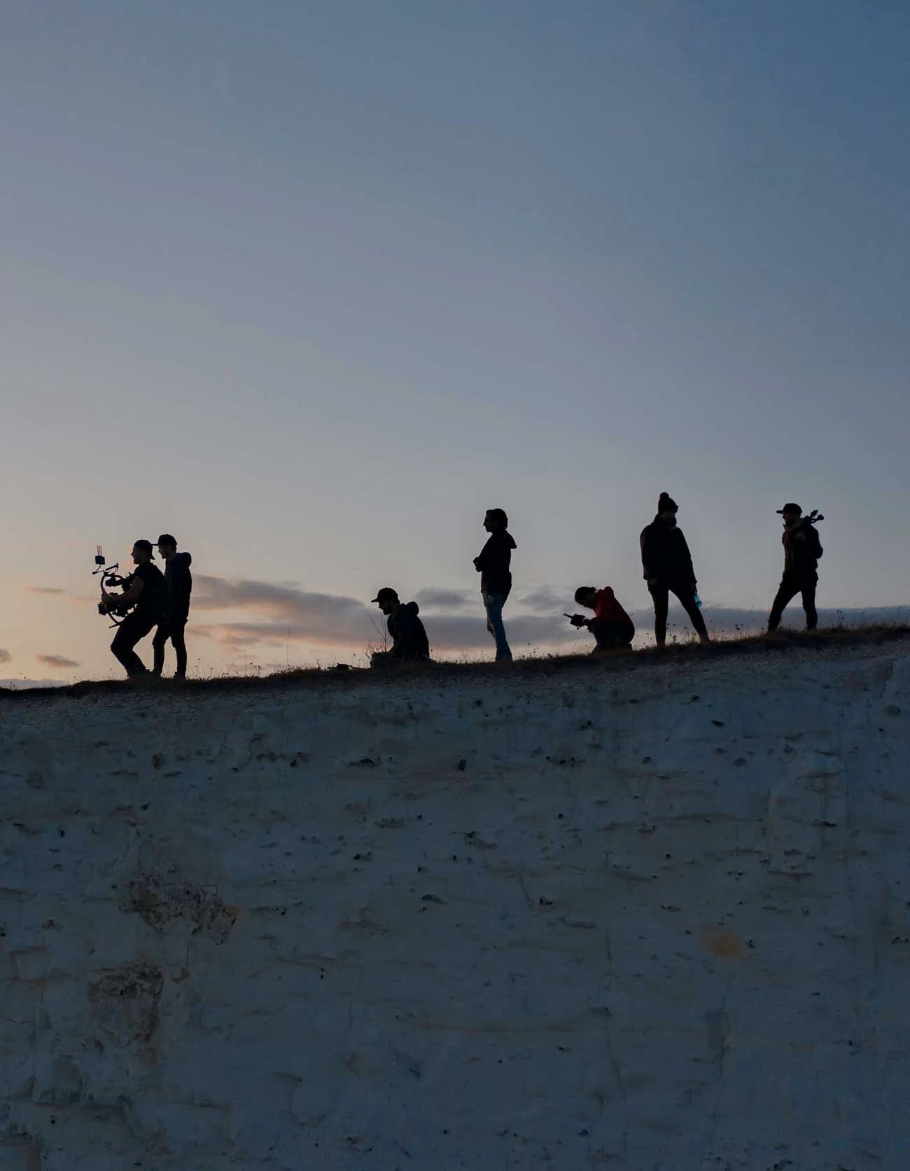 filmcrew silhouettes on a cliff edge drone photo