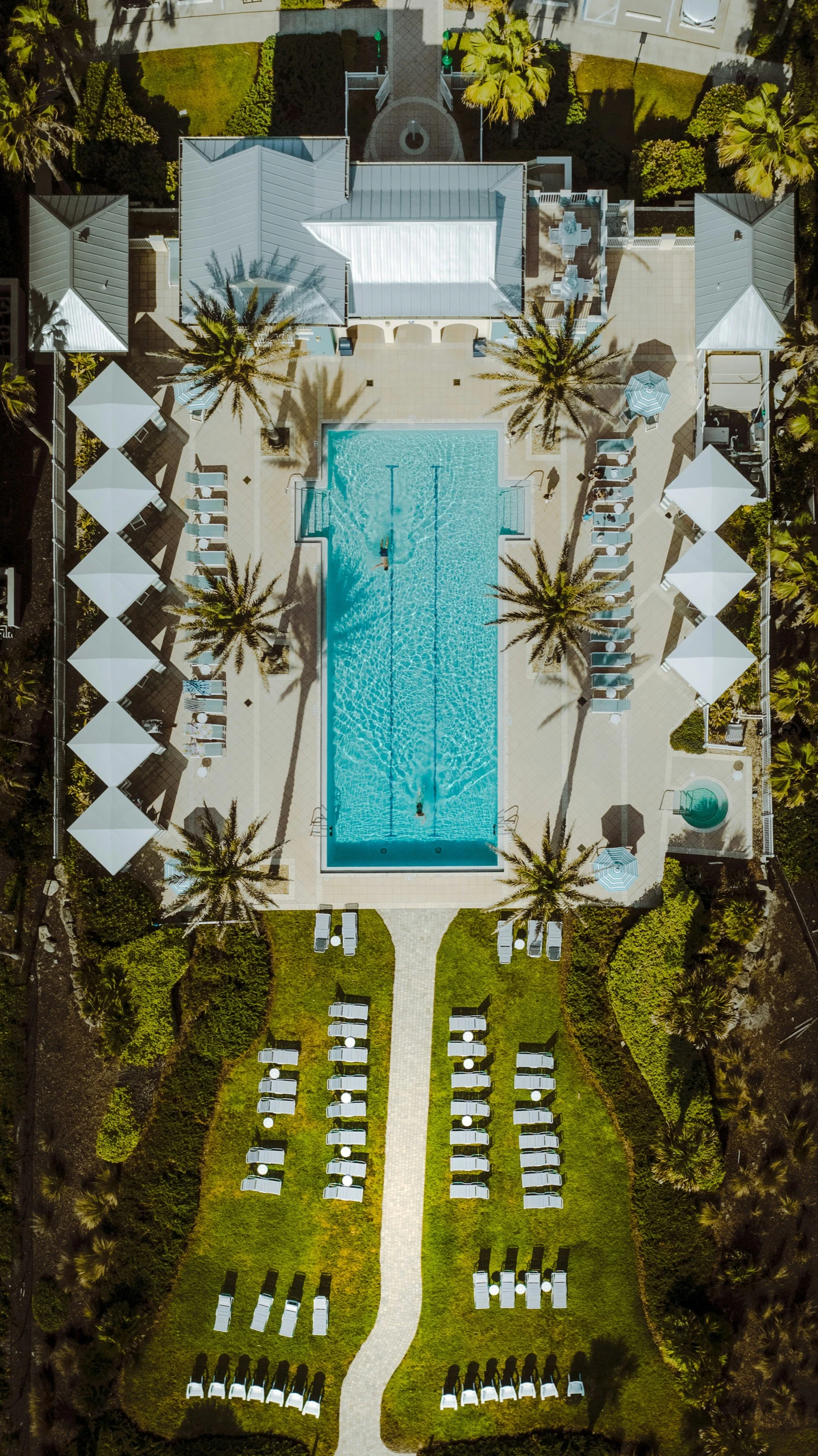 Aerial view of a hotel pool framed by cabanas and palms