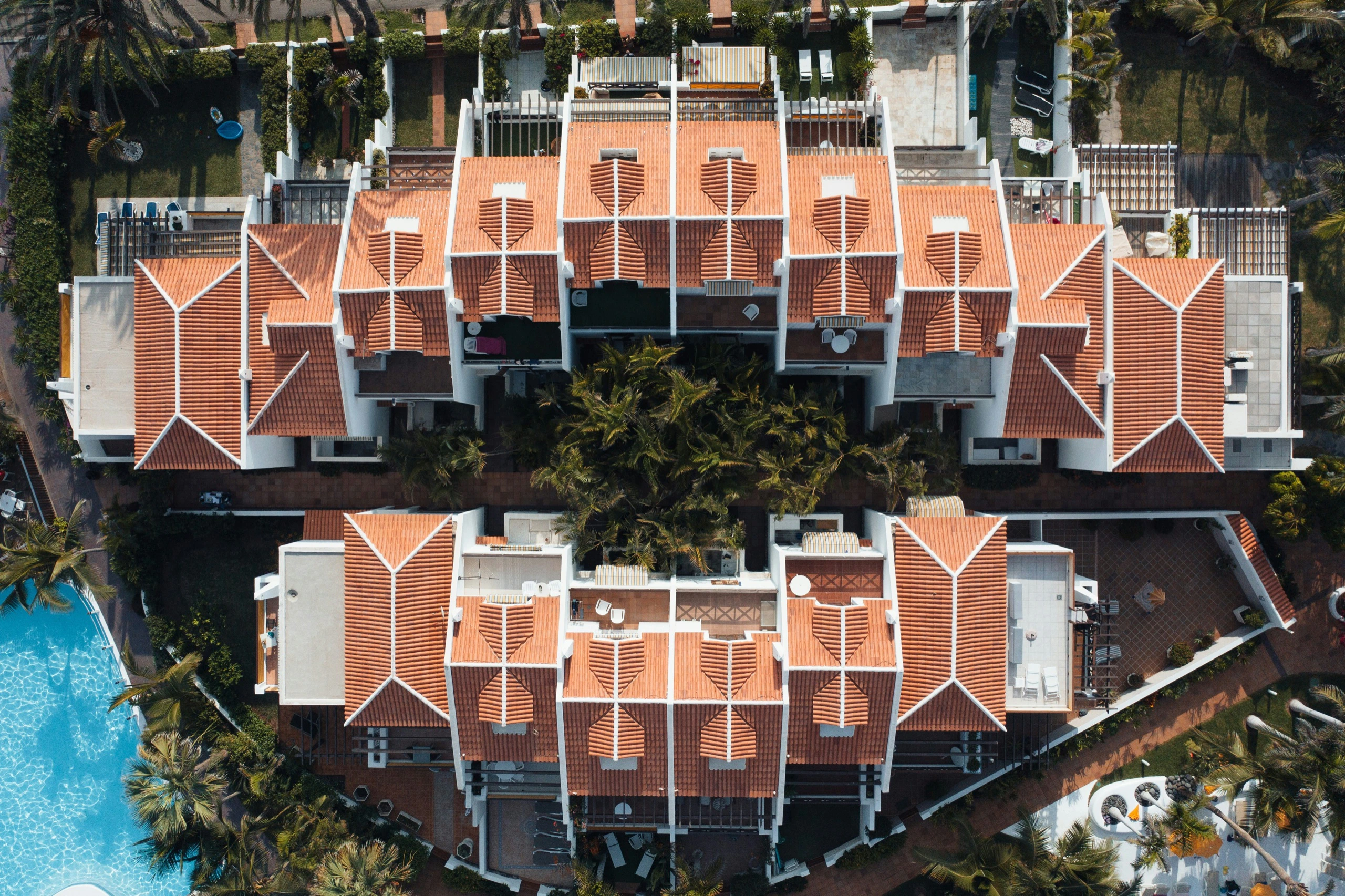 Aerial view of resort villas with terracotta roofs beside a pool